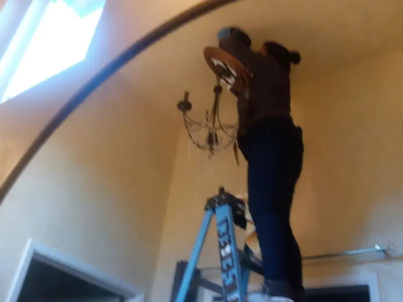 Electrician installing a chandelier in a West View residence